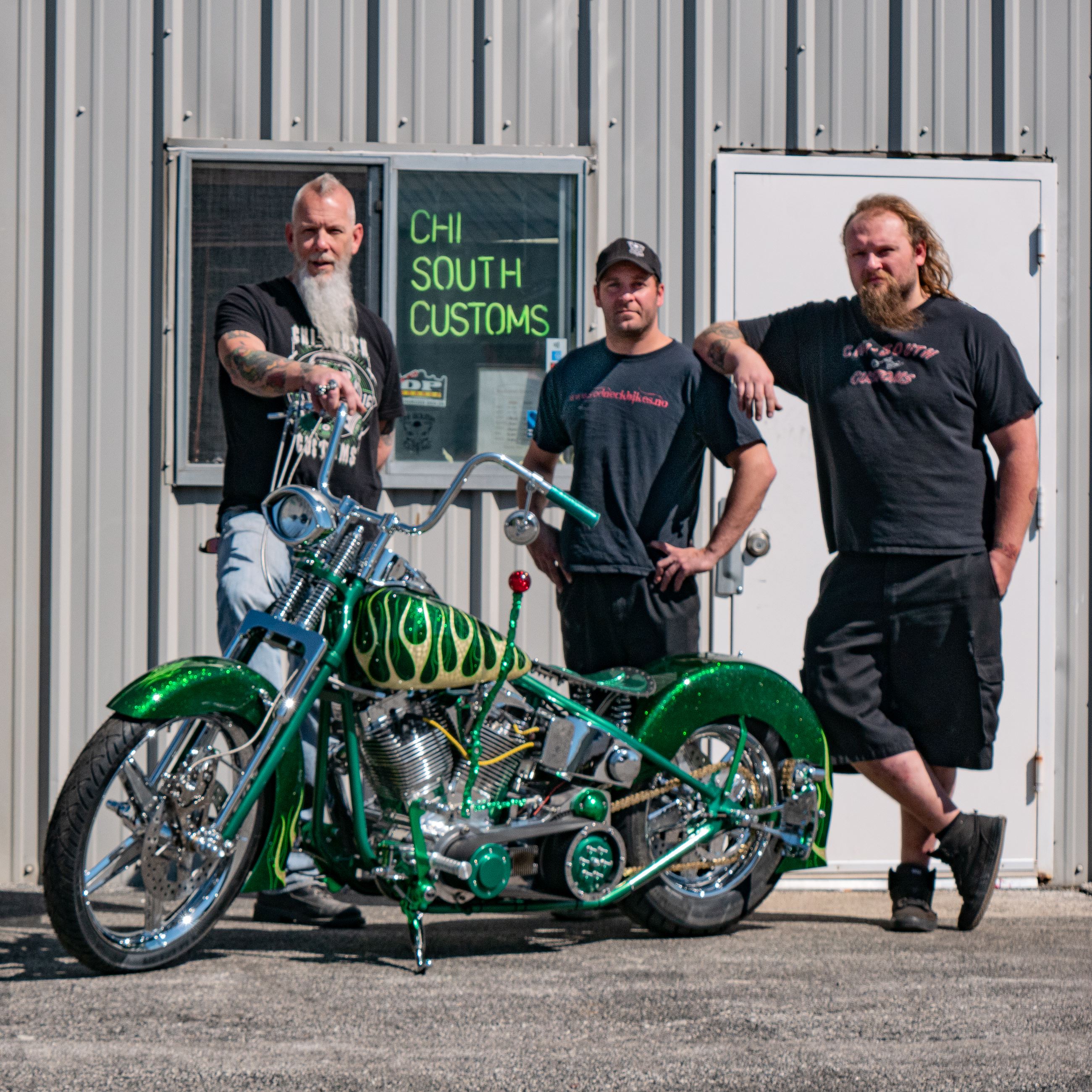 3 males standing by motorcycle