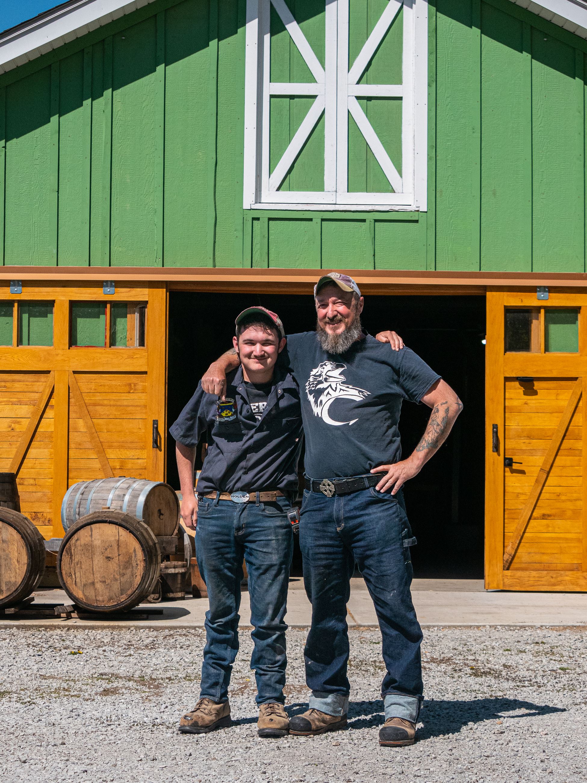 two men standing in front of barn